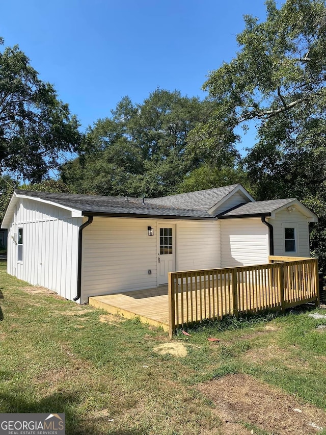 rear view of property featuring a yard and a deck