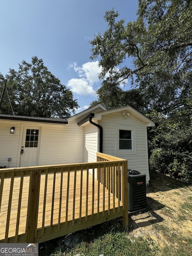 back of property with central AC unit and a deck