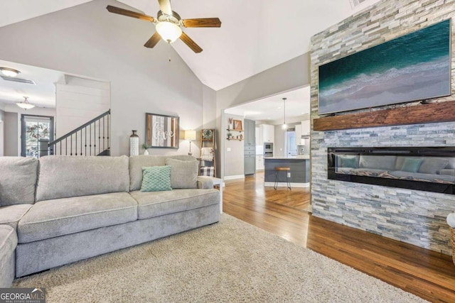 living room with a fireplace, hardwood / wood-style floors, high vaulted ceiling, and ceiling fan