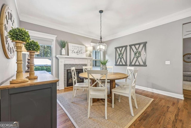 dining room featuring a fireplace, crown molding, dark hardwood / wood-style flooring, and a notable chandelier