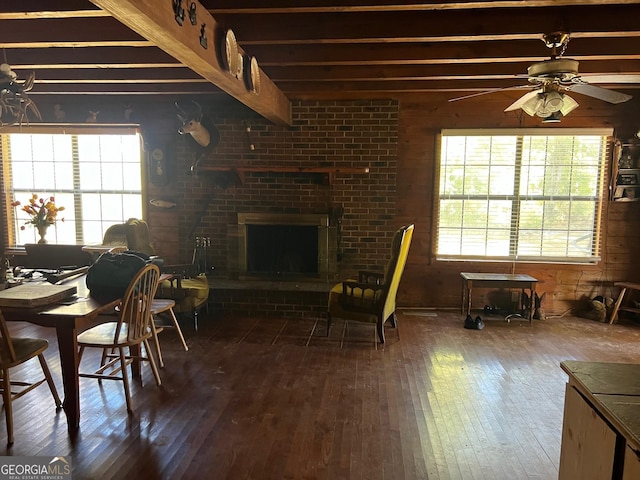 dining area with beam ceiling, ceiling fan, dark hardwood / wood-style floors, and a brick fireplace