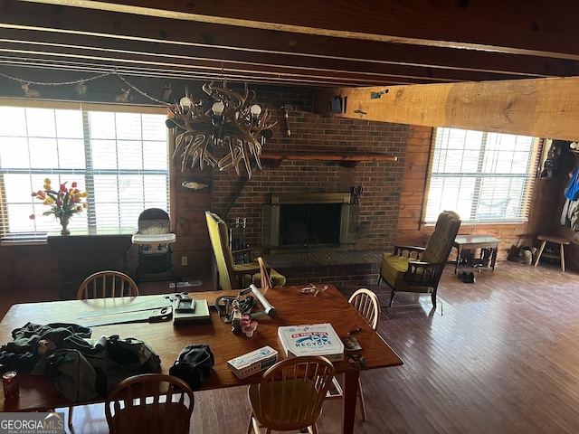 dining room with hardwood / wood-style floors, a brick fireplace, and beam ceiling