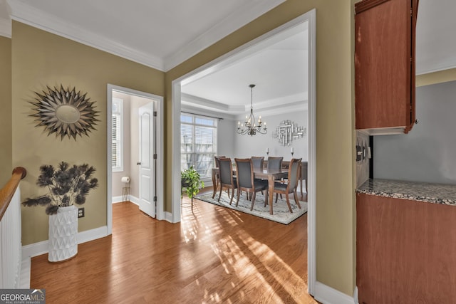 entrance foyer featuring an inviting chandelier, ornamental molding, and light hardwood / wood-style flooring