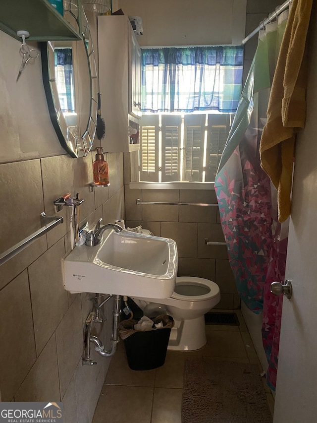 bathroom with tile patterned floors, sink, toilet, tile walls, and curtained shower