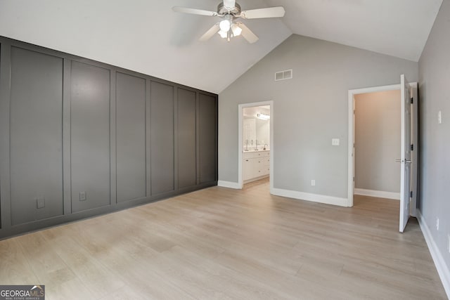 unfurnished bedroom featuring light wood-type flooring, high vaulted ceiling, ensuite bath, and ceiling fan