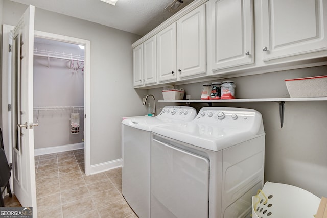 clothes washing area with cabinets, washing machine and dryer, light tile patterned floors, and a textured ceiling