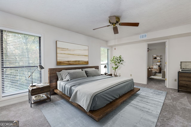 carpeted bedroom with multiple windows, ceiling fan, and a textured ceiling