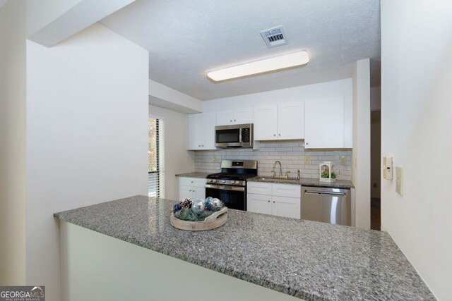 kitchen with decorative backsplash, white cabinetry, sink, and appliances with stainless steel finishes