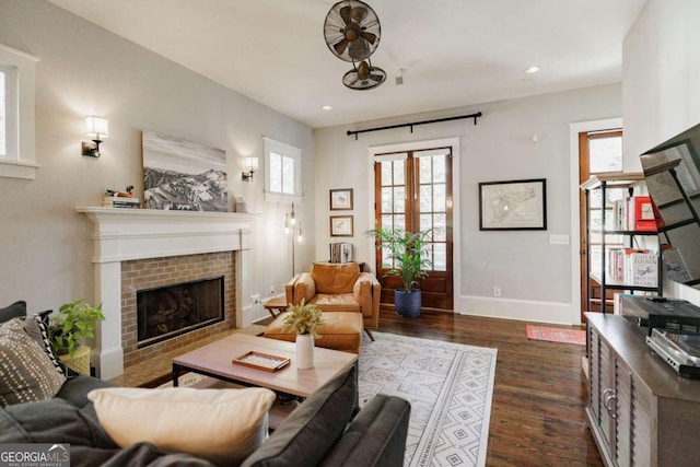 living room with french doors, a brick fireplace, and dark wood-type flooring