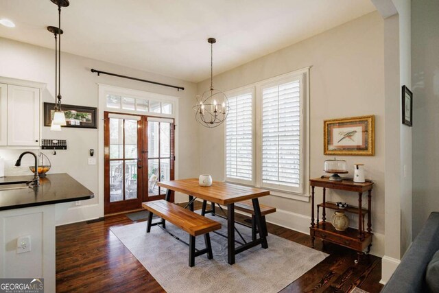 dining area with a wealth of natural light, dark hardwood / wood-style flooring, a chandelier, and french doors