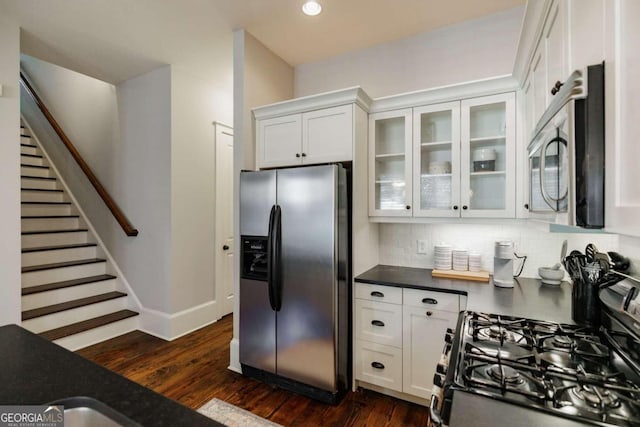 kitchen with tasteful backsplash, white cabinetry, stainless steel appliances, and dark hardwood / wood-style floors