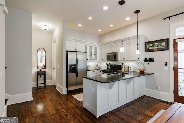 kitchen with kitchen peninsula, plenty of natural light, pendant lighting, and appliances with stainless steel finishes