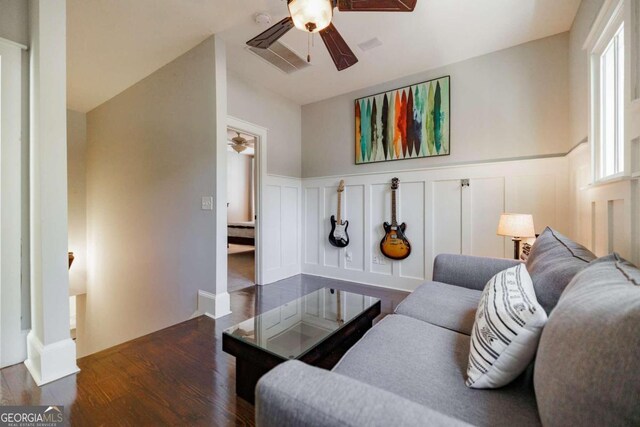 living room with ceiling fan, lofted ceiling, and dark wood-type flooring