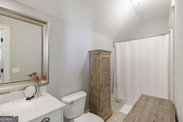 bathroom featuring tile patterned flooring, vanity, toilet, and vaulted ceiling