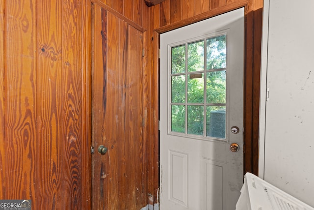 doorway to outside with wooden walls