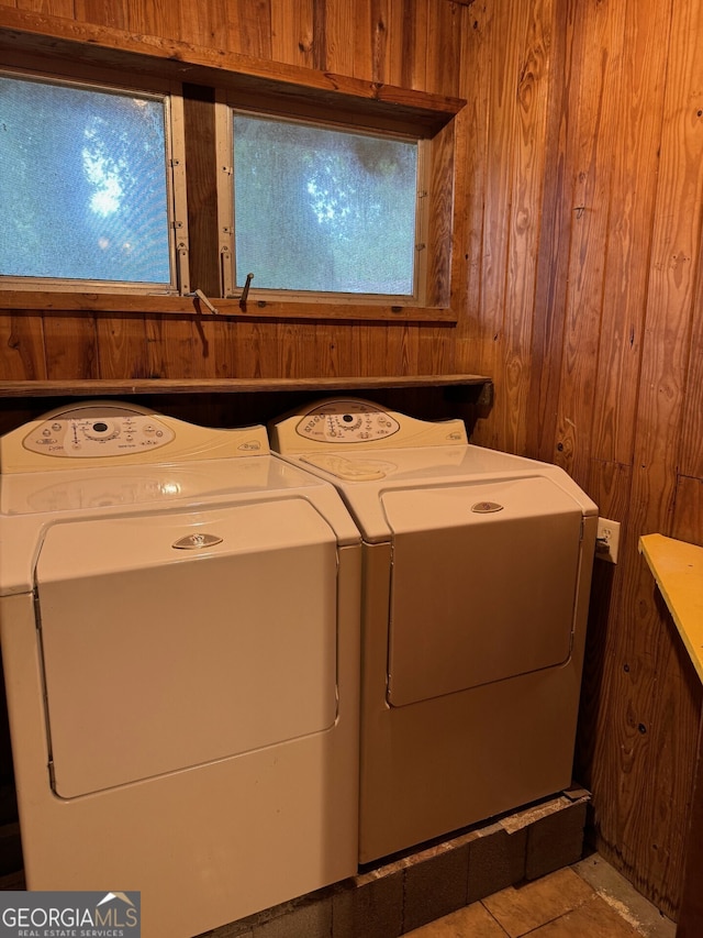 laundry area featuring independent washer and dryer, light tile patterned floors, and wooden walls