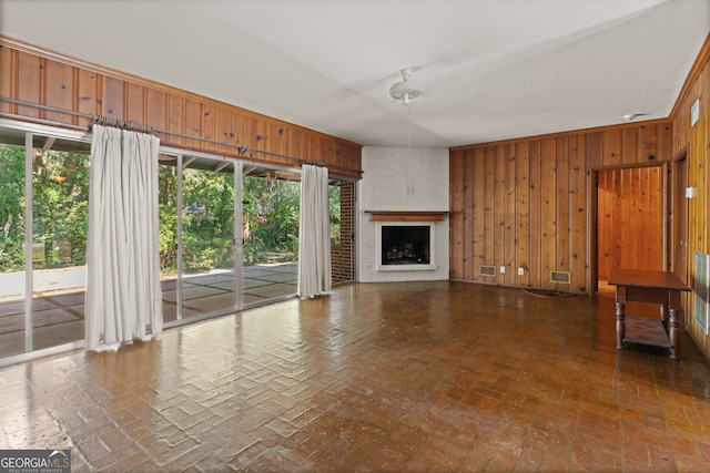 unfurnished living room featuring a fireplace and wooden walls