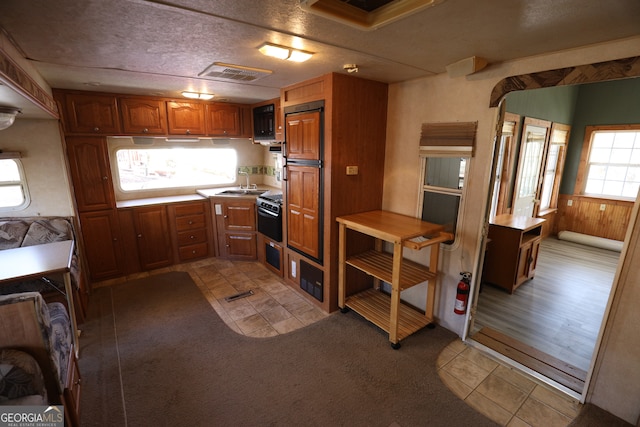 kitchen featuring wood walls, sink, light hardwood / wood-style floors, and a textured ceiling