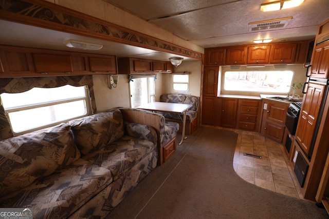 kitchen with a textured ceiling, kitchen peninsula, sink, and dark colored carpet