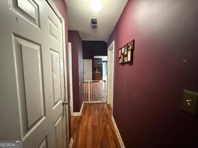 corridor featuring a textured ceiling and hardwood / wood-style flooring