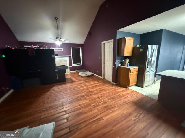 kitchen featuring ceiling fan, light hardwood / wood-style floors, stainless steel refrigerator with ice dispenser, and high vaulted ceiling