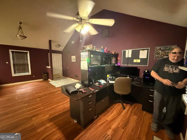 home office featuring ceiling fan, wood-type flooring, and vaulted ceiling