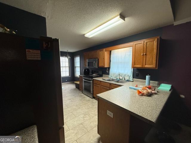 kitchen featuring a textured ceiling, sink, kitchen peninsula, and stainless steel appliances