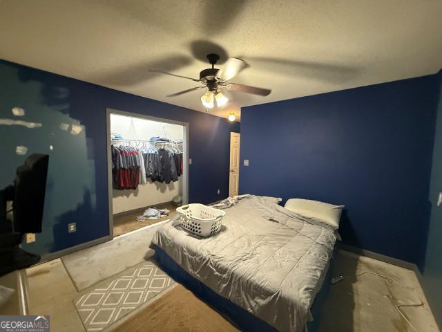 bedroom featuring ceiling fan, a walk in closet, a textured ceiling, and a closet