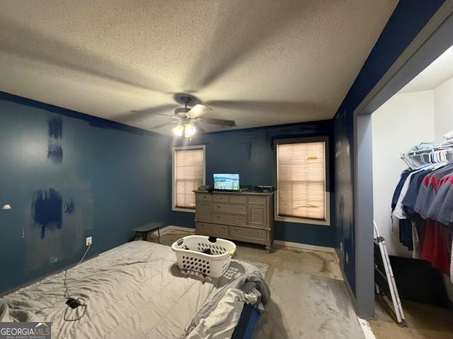 carpeted bedroom featuring ceiling fan and a textured ceiling