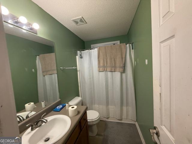 full bathroom featuring a textured ceiling, vanity, shower / bath combo, and toilet