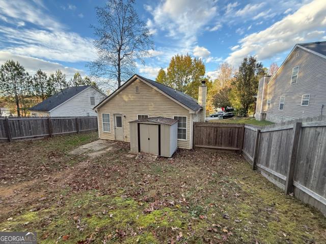 rear view of property featuring a storage shed