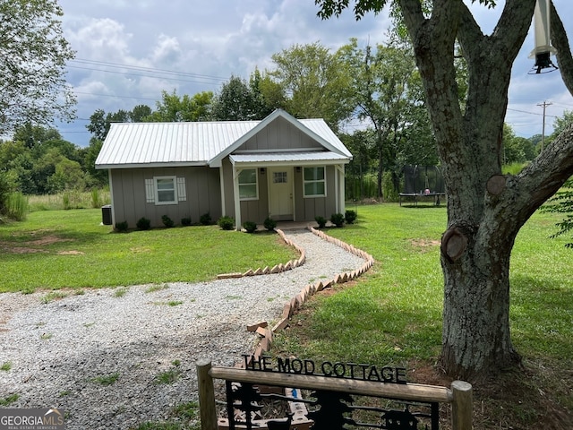 single story home featuring a trampoline and a front lawn