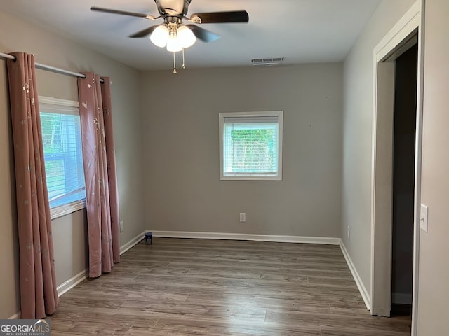 unfurnished room featuring ceiling fan, a healthy amount of sunlight, and wood-type flooring