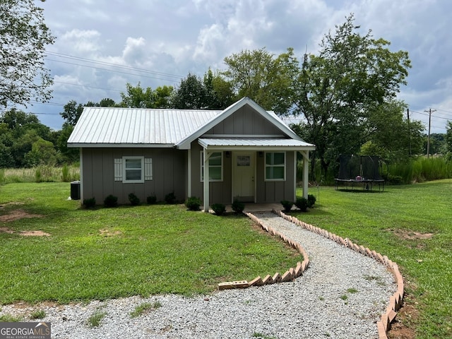 view of front of house with a front yard, a trampoline, and central AC unit