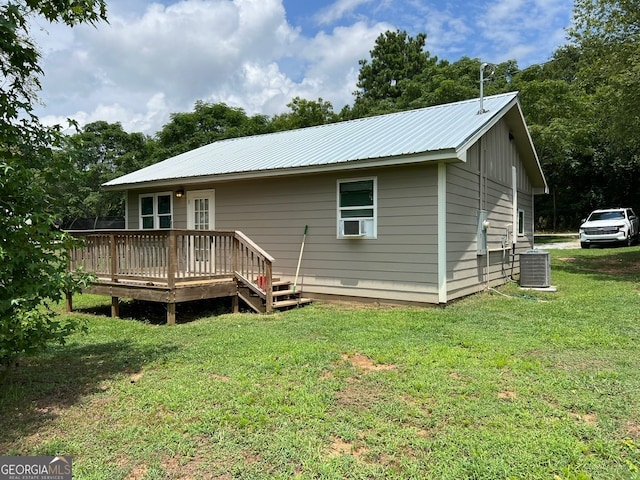 rear view of house with a lawn, a wooden deck, and central AC unit