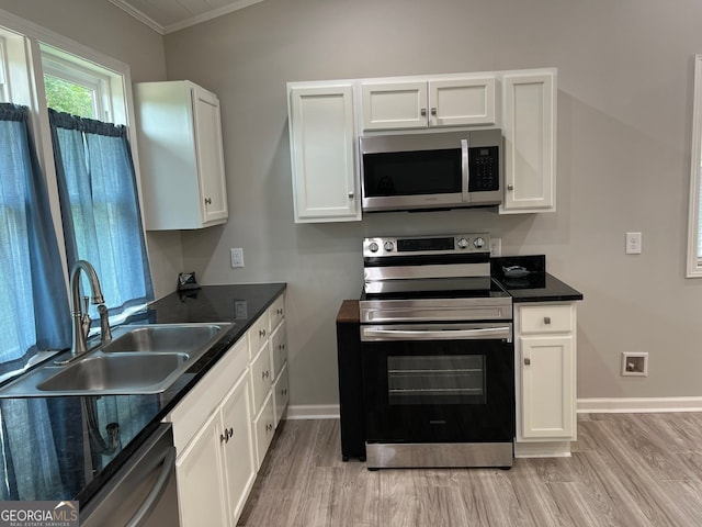 kitchen featuring light wood-type flooring, stainless steel appliances, crown molding, sink, and white cabinetry