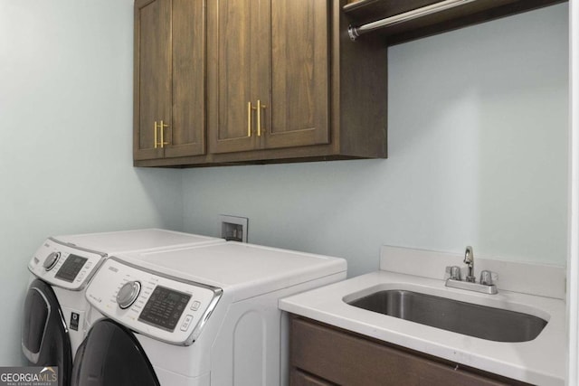 clothes washing area with washing machine and clothes dryer, sink, and cabinets