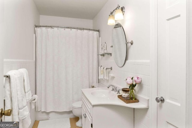 bathroom featuring vanity, toilet, and tile walls