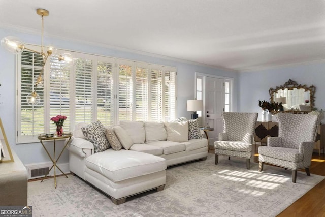 living room with a wealth of natural light, hardwood / wood-style floors, crown molding, and an inviting chandelier