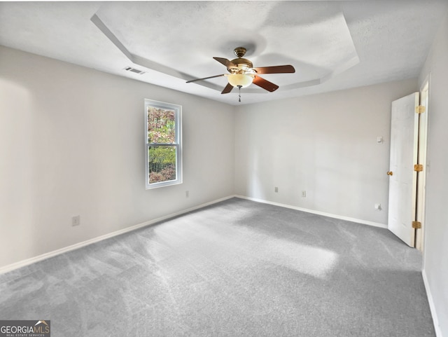 carpeted spare room with a tray ceiling, ceiling fan, and a textured ceiling