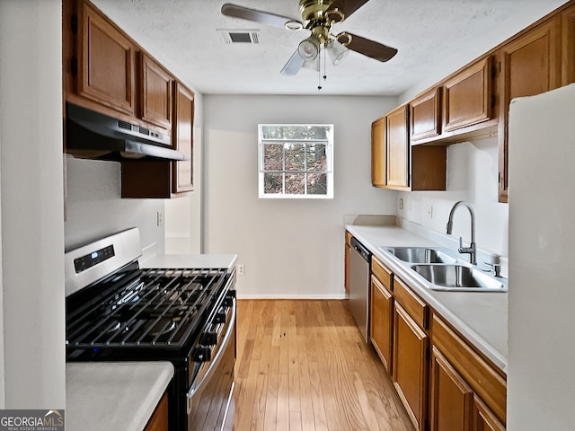 kitchen with appliances with stainless steel finishes, light hardwood / wood-style floors, ceiling fan, and sink