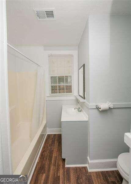 full bathroom featuring shower / bath combination with curtain, vanity, wood-type flooring, and toilet