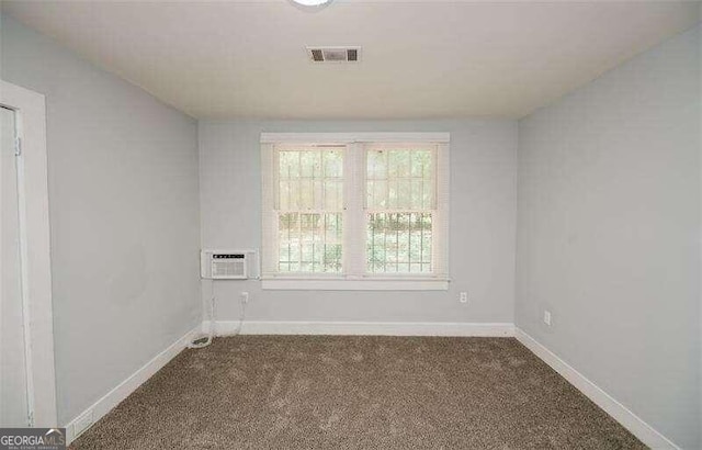 carpeted spare room featuring a wall unit AC