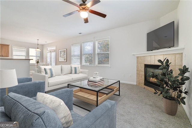 carpeted living room with a tile fireplace and ceiling fan