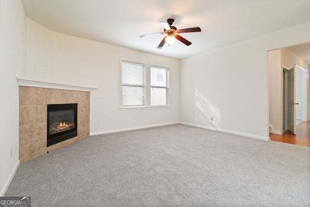 unfurnished living room with ceiling fan, light colored carpet, and a tile fireplace