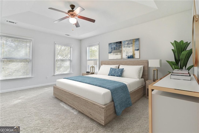 carpeted bedroom featuring a raised ceiling and ceiling fan