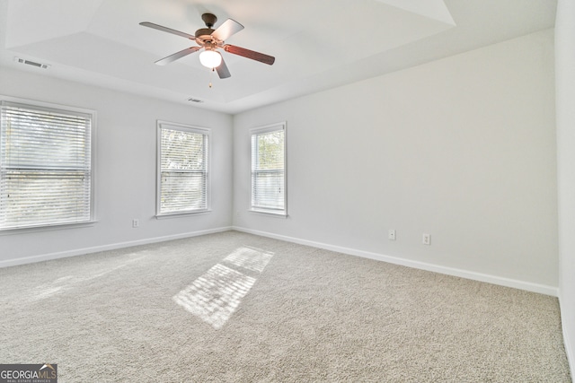 carpeted spare room with a tray ceiling and ceiling fan