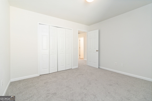 unfurnished bedroom featuring light carpet and a closet