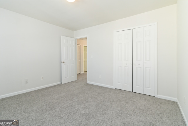 unfurnished bedroom featuring light carpet and a closet