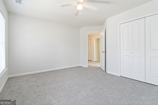 unfurnished bedroom with ceiling fan, a closet, and light carpet